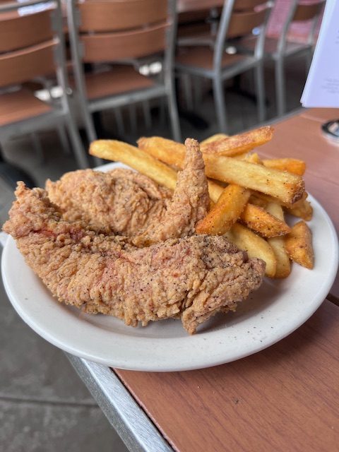Gluten-free fried chicken and seasoned fries served on a white plate at The Post restaurant in Denver.