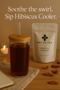 Insulated white tumbler filled with dark red hibiscus tea, topped with a bamboo lid and centered glass straw, sits on a textured linen cloth beside a notebook, candle, and Art of Tea’s Hibiscus Cooler pouch. Soft lighting and autumn accents create a peaceful tea ritual scene with the words ‘Soothe the swirl. Sip Hibiscus Cooler.’ overlaid above.