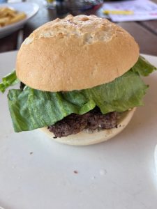 Gluten-free burger served on a white plate at North Side Tavern in Denver. The juicy patty is stacked with melted cheese, lettuce, and tomato, nestled in a golden gluten-free bun with a side of crisp fries—perfectly plated for a satisfying Celiac-friendly meal.