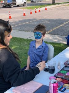 A young boy sitting patiently while getting his face painted like Stitch from Lilo & Stitch at the library’s summer reading kickoff event.