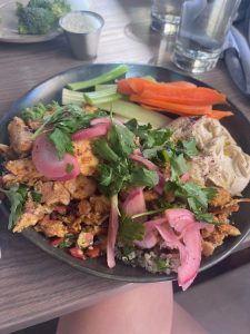 Colorful chicken shawarma plate served on a blue dish at Boychik in Stanley Marketplace. The meal features grilled chicken, quinoa, hummus, and fresh vegetables, artfully arranged for a vibrant, gluten-free Mediterranean lunch.