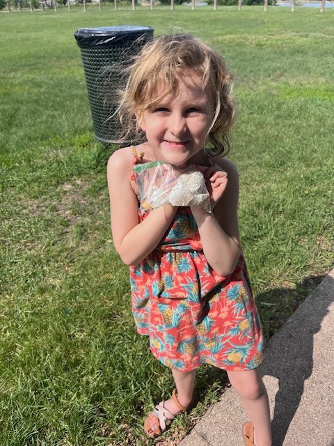 Young girl holding a bag filled with crushed geode pieces, showcasing the glittering rock fragments inside.