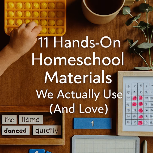 Flat-lay photo of hands-on homeschool materials arranged on a wooden surface. Includes a yellow popper multiplication board being pressed by a child’s hand, magnetic sentence tiles forming “the llama danced quietly,” blue fraction tiles showing ¾, a hundred chart with red counters, and a mini whiteboard with “10×2=20” written in purple. A mug of tea and eucalyptus sprigs add warmth. Title text reads “11 Hands-On Homeschool Materials We Actually Use (And Love)” in white, centered above the materials.